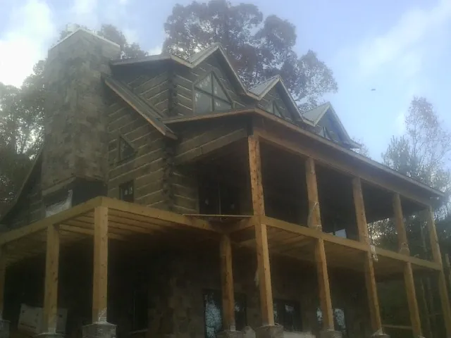 Stone chimney and dormers on a large log home with a timber porch in Coleman