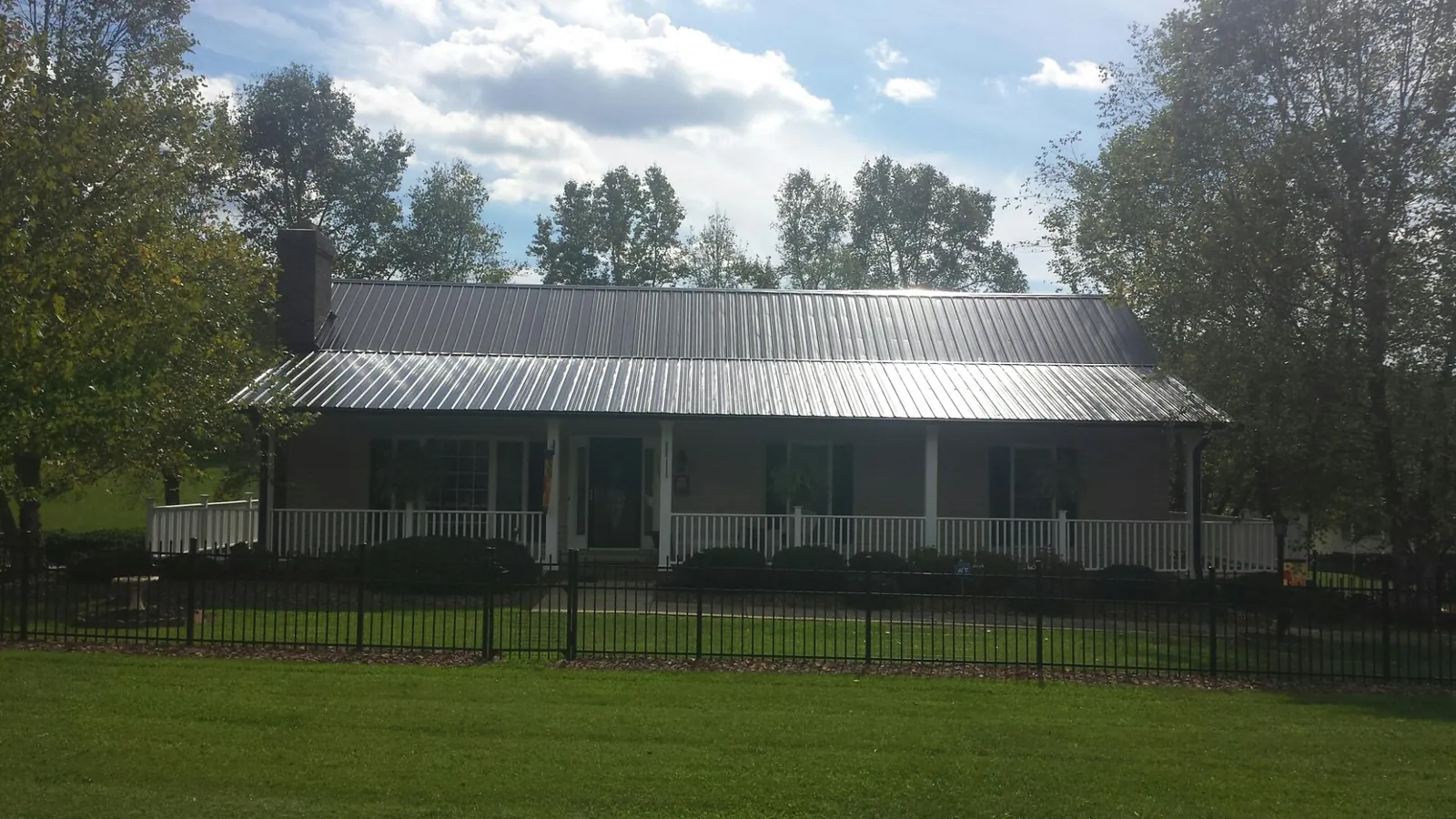 Gray metal roof on a brick ranch with a full width front porch — Gutter Guard Installation work by our crew in Coleman